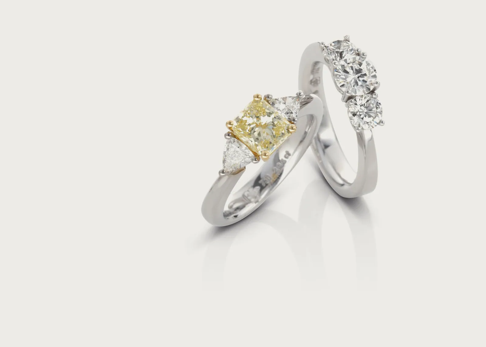 Trilogie: Fancy Yellow Cushioncut-Diamant in Weißgold, begleitet von einem strahlenden Diamant-Trio — zwei Ringe, eine Geschichte.
