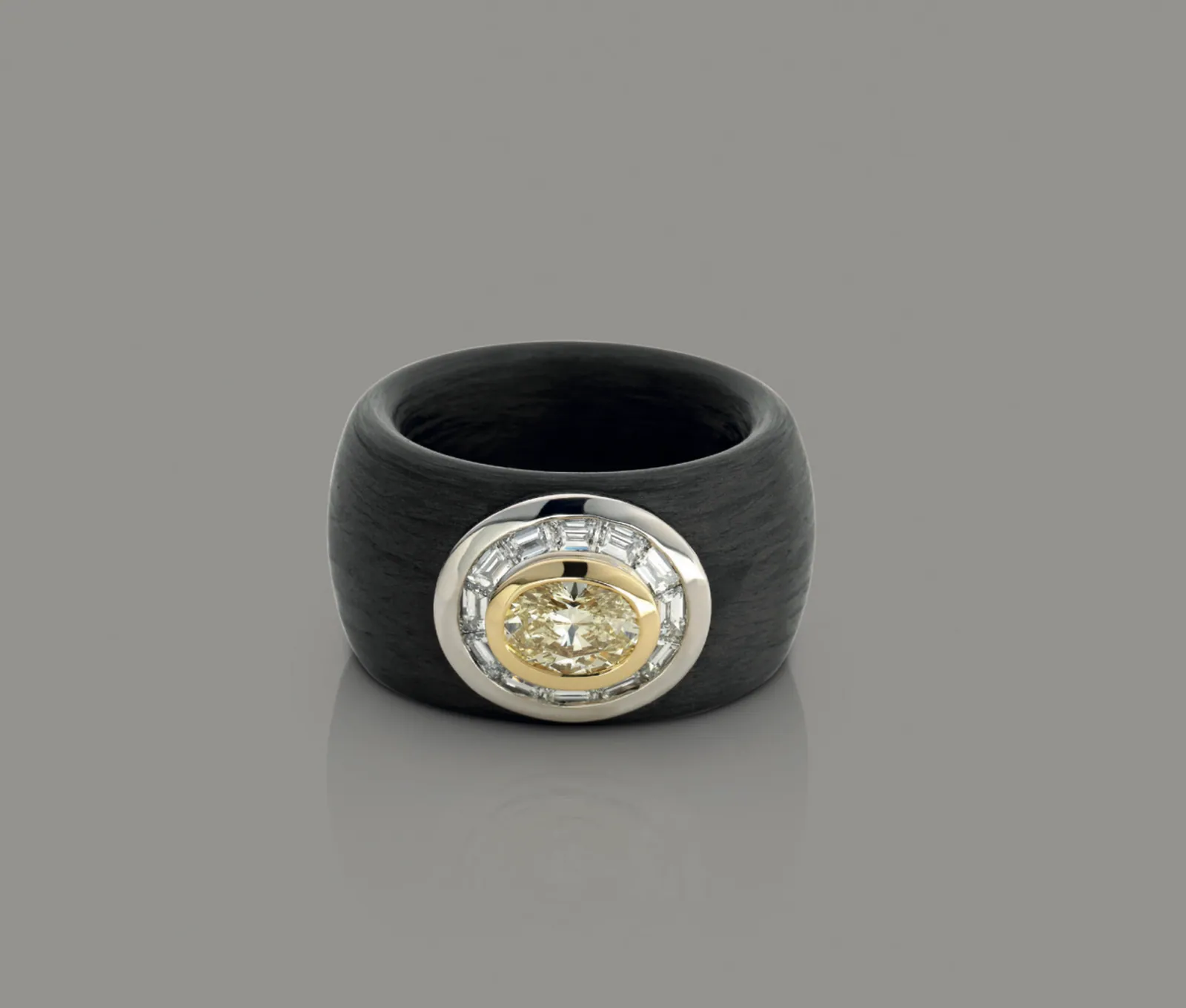 Carbon: Light Yellow Diamant in Gelbgold, umschmeichelt von Baguette-Diamanten in Weißgold — getragen von einer Schiene aus Carbon.